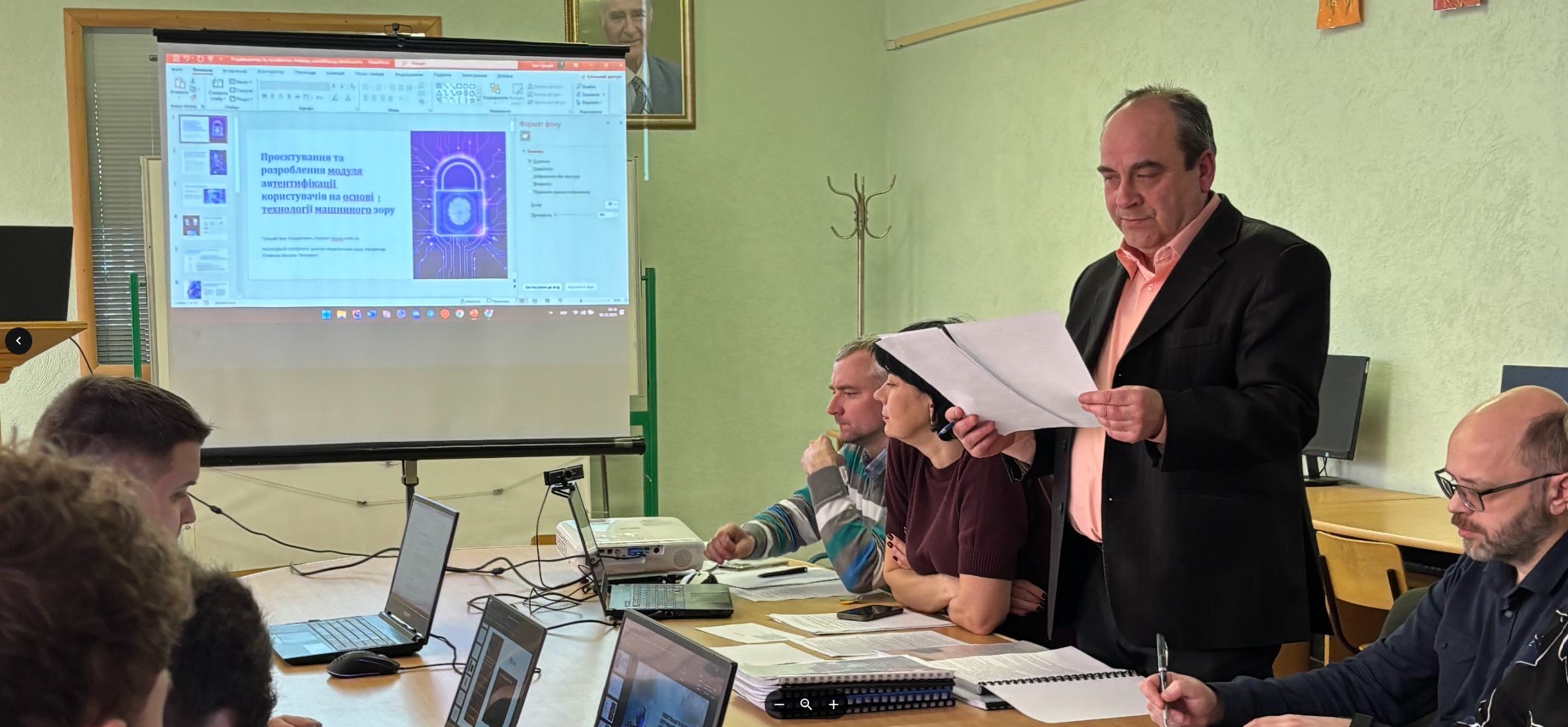 Голова ЕК Михайло Касянчук зачитує рецензію на кваліфікаційну роботу  «Проєктування та розроблення модуля автентифікації користувачів на основі технології маш»